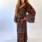 Woman wearing a patterned dress with bell sleeves against a white background