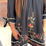 Black dress with floral embroidery and tied sleeves worn by a person.