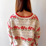 Person wearing a floral-patterned sweater against a plain background