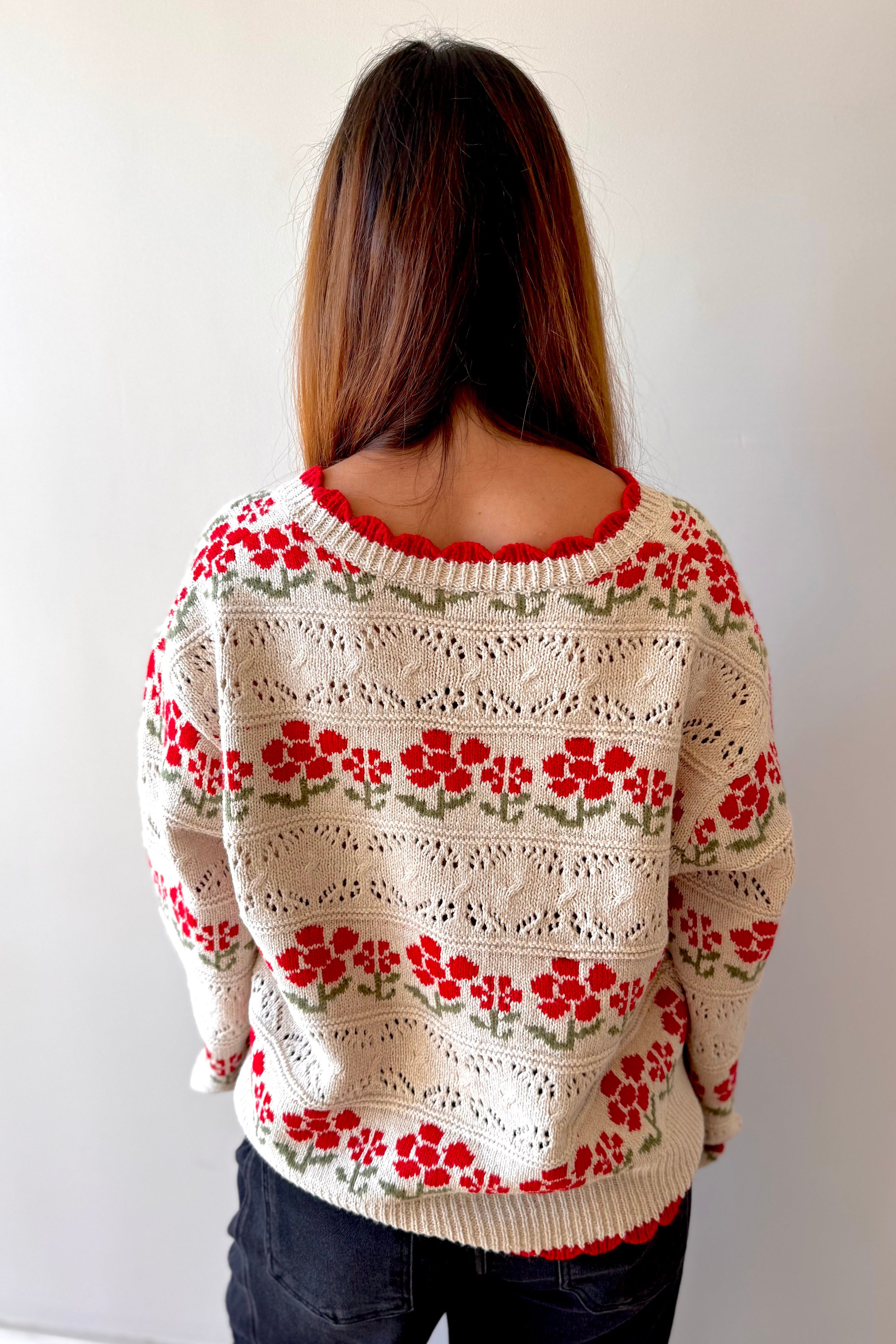 Person wearing a floral-patterned sweater against a plain background