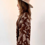 Person wearing a brown patterned sweater and beige hat on a white background
