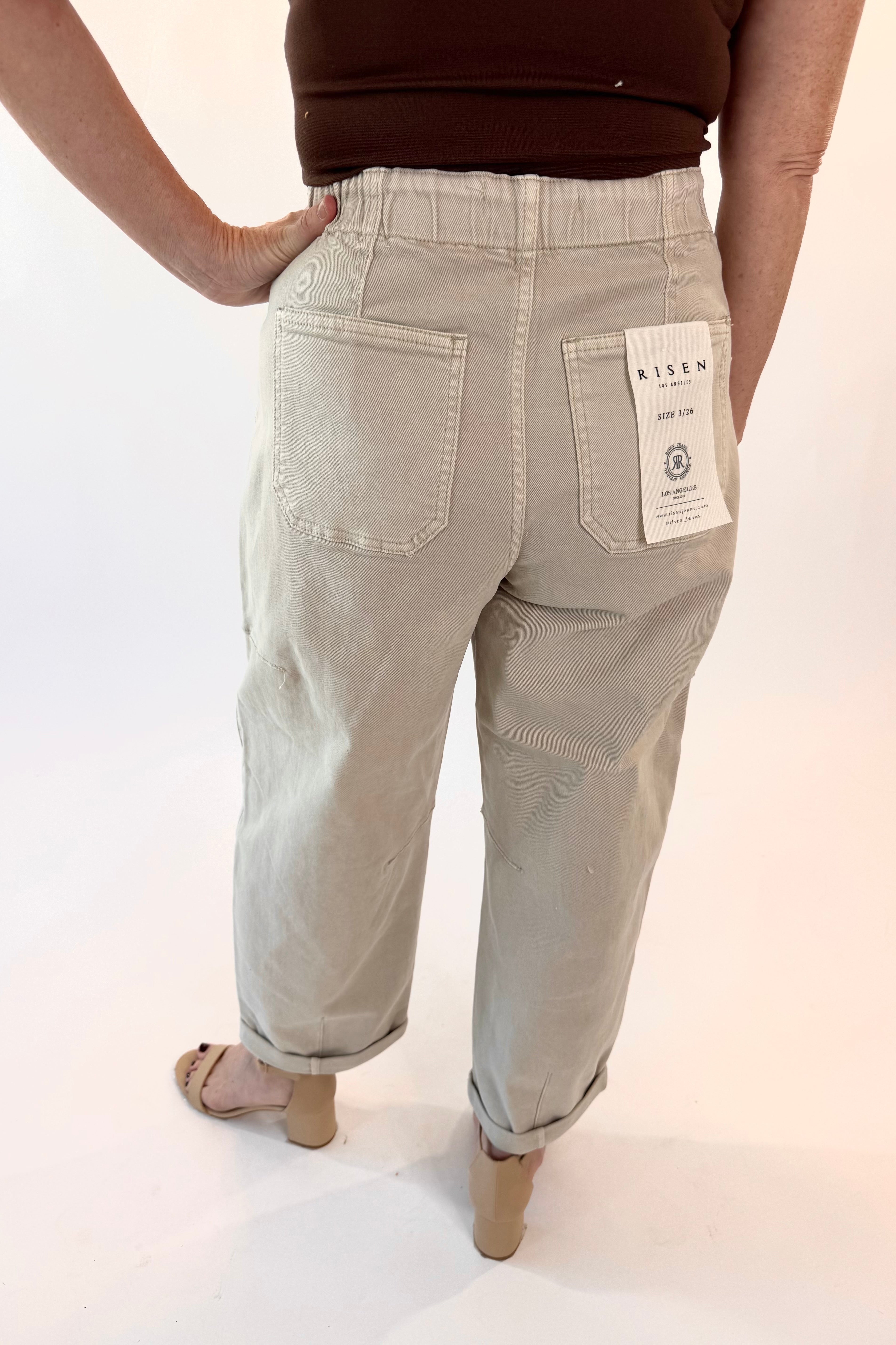 Light-colored pants with a visible brand tag on a plain background