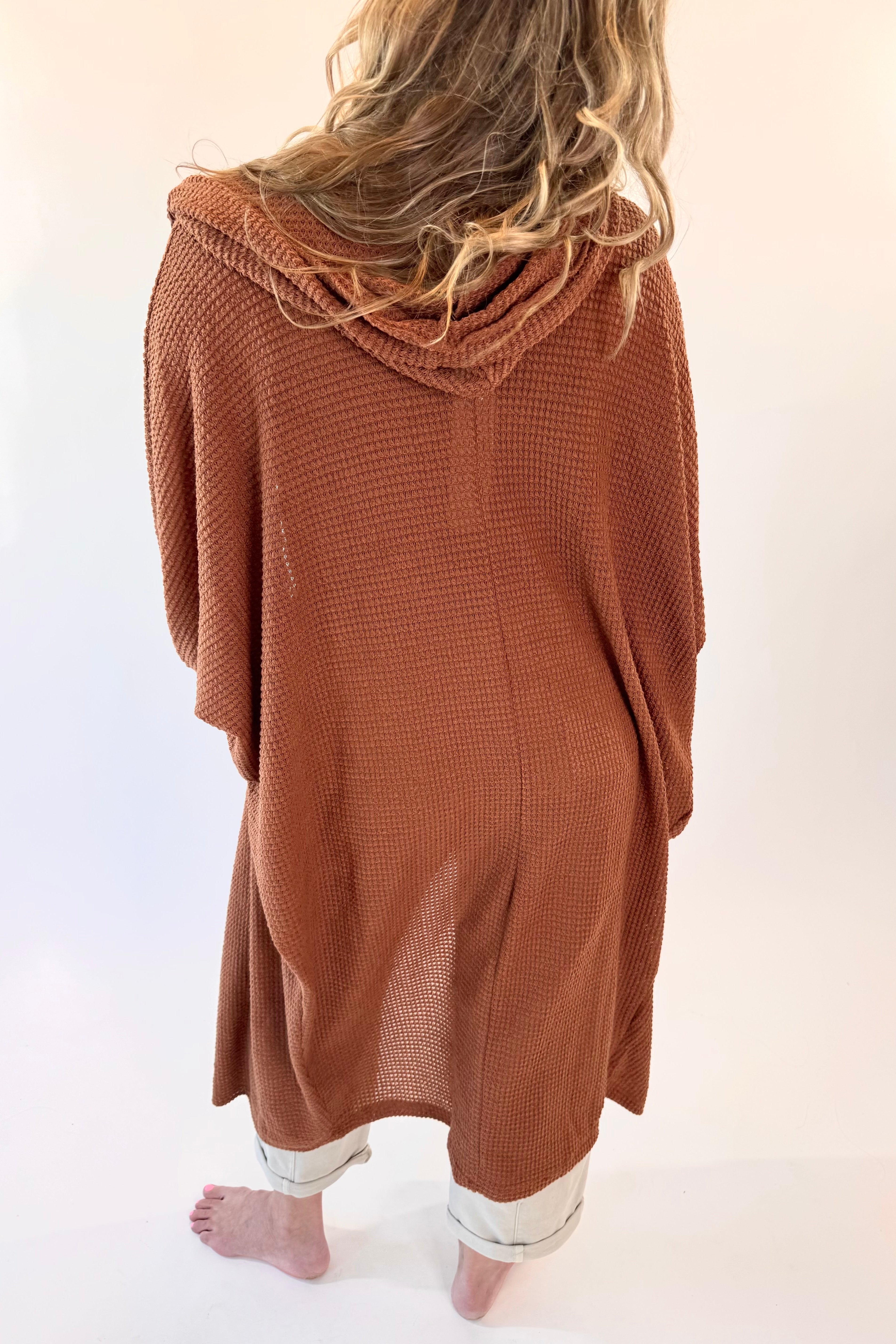 Person wearing a brown hooded garment on a white background