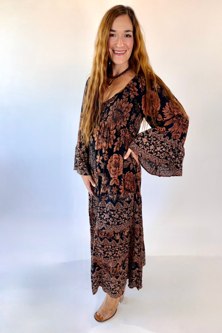 Woman wearing a patterned dress with bell sleeves against a white background