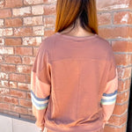 Person wearing a brown outfit standing in front of a brick wall.