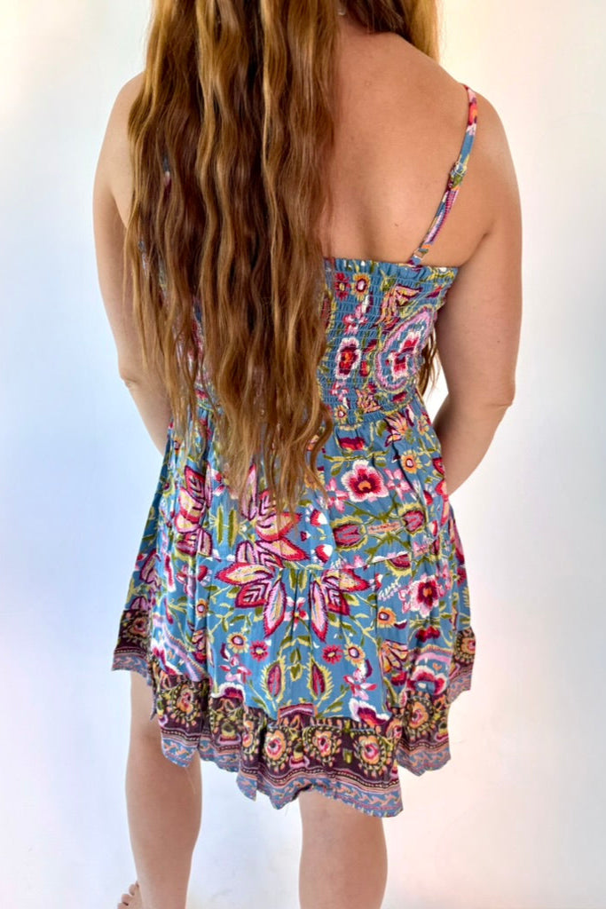 Woman wearing a colorful floral dress against a light background