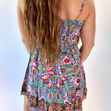 Woman wearing a colorful floral dress against a light background