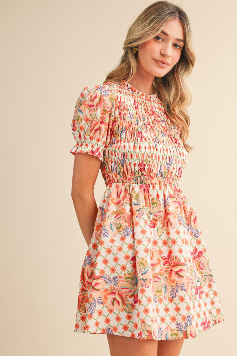 Woman wearing a floral dress against a beige background | Wildflower Whimsy Smocked Mini Dress