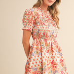 Woman wearing a floral dress against a beige background | Wildflower Whimsy Smocked Mini Dress