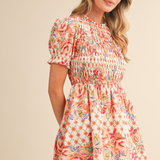 Woman wearing a floral dress against a beige background | Wildflower Whimsy Smocked Mini Dress