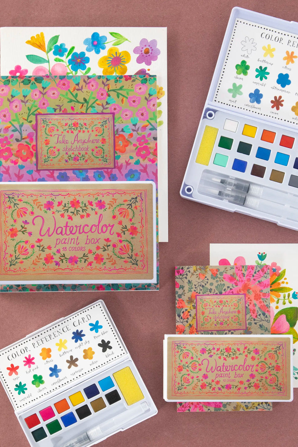 Colorful watercolor paint sets with floral designs on a brown background