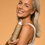 Woman holding a bottle of Petalane product against an orange background