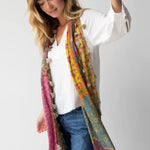 Woman wearing a colorful scarf with floral patterns and tassels on a white background