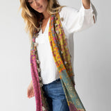 Woman wearing a colorful scarf with floral patterns and tassels on a white background