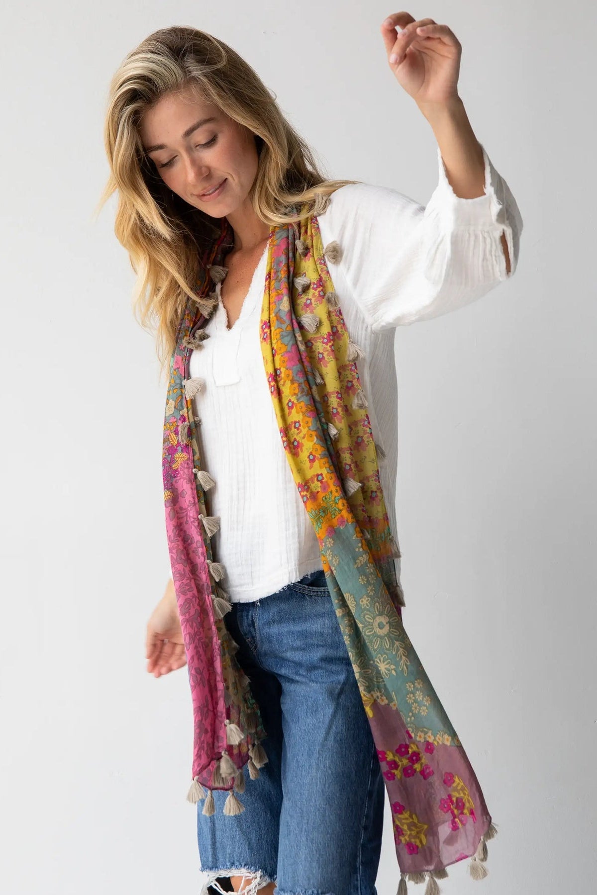 Woman wearing a colorful scarf with floral patterns and tassels on a white background