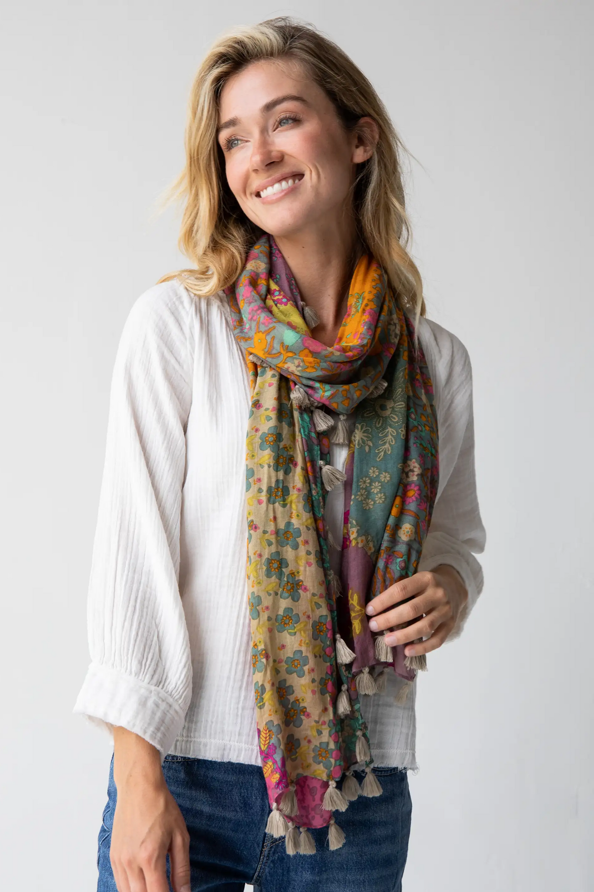 Woman wearing a colorful floral scarf on a plain background