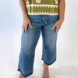 Woman wearing a green patterned shirt and blue jeans on a white background