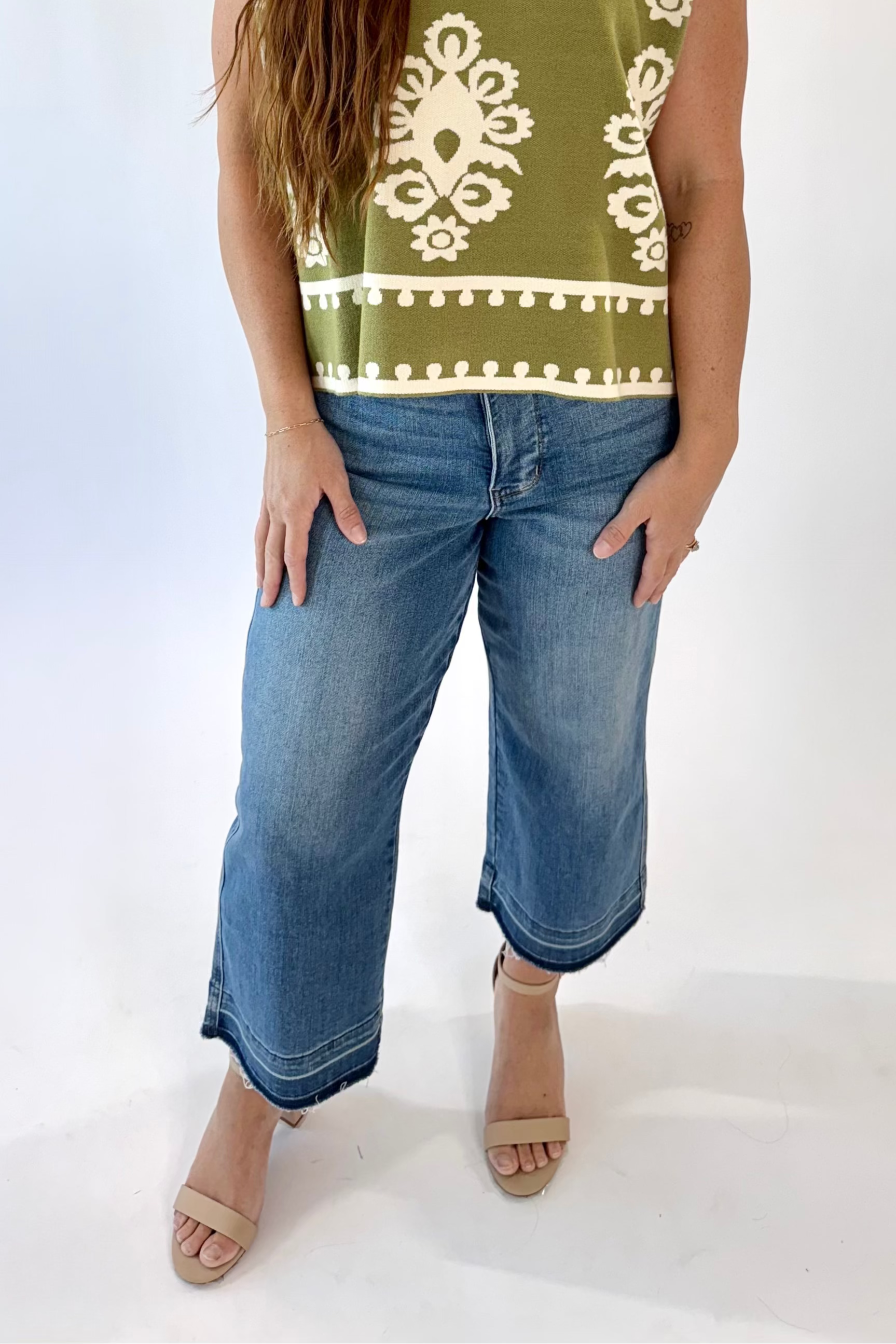 Woman wearing a green patterned shirt and blue jeans on a white background