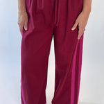 Maroon pants with pink accents worn by a person on a white background