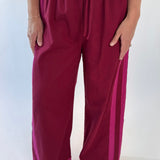 Maroon pants with pink accents worn by a person on a white background