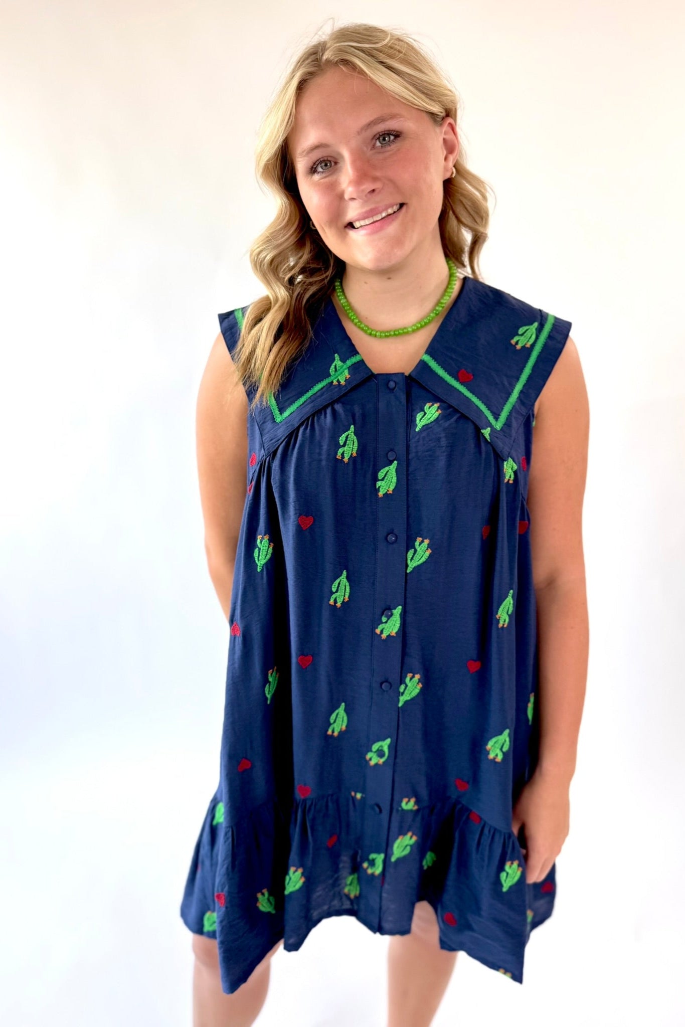 Young girl wearing a navy dress with green and red patterns on a white background