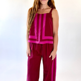 Woman wearing a magenta sleeveless top and wide-leg pants on a white background