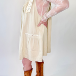 Person wearing a beige dress and brown boots on a white background