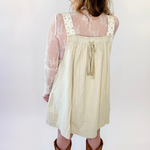 Woman wearing a beige dress with sheer sleeves against a white background