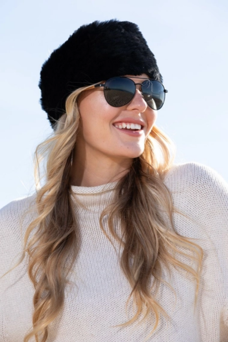 Woman wearing a black fur hat and sunglasses with a white background