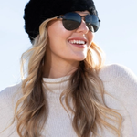 Woman wearing a black fur hat and sunglasses with a white background