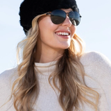 Woman wearing a black fur hat and sunglasses with a white background