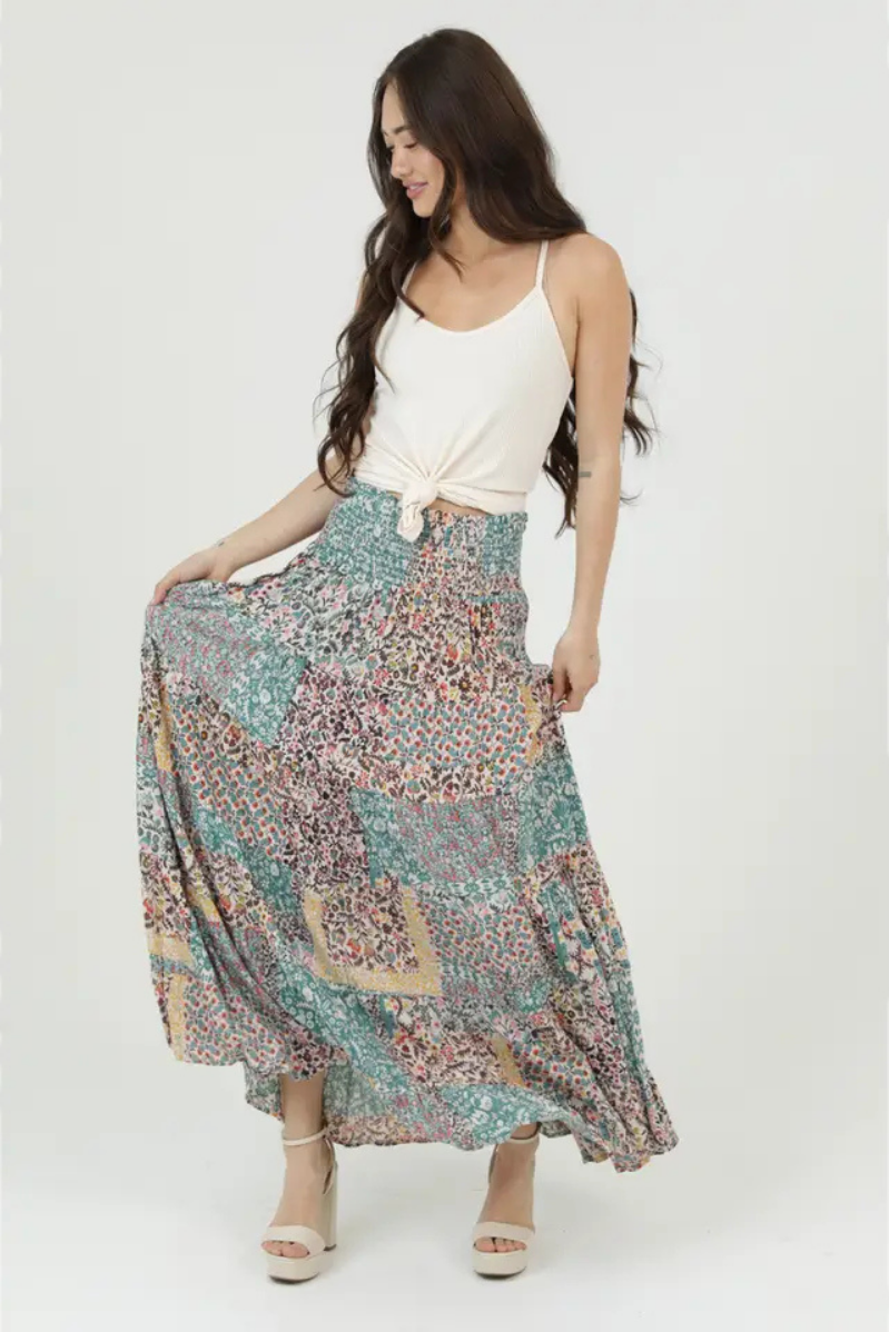 Woman wearing a long, patterned skirt with a white top on a white background