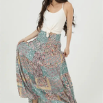 Woman wearing a long, patterned skirt with a white top on a white background
