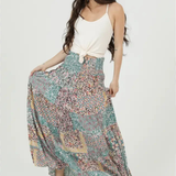 Woman wearing a long, patterned skirt with a white top on a white background