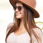 Woman wearing a brown hat and sunglasses with a blurred natural background