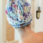 Person with a floral towel wrapped around their head in a bathroom setting