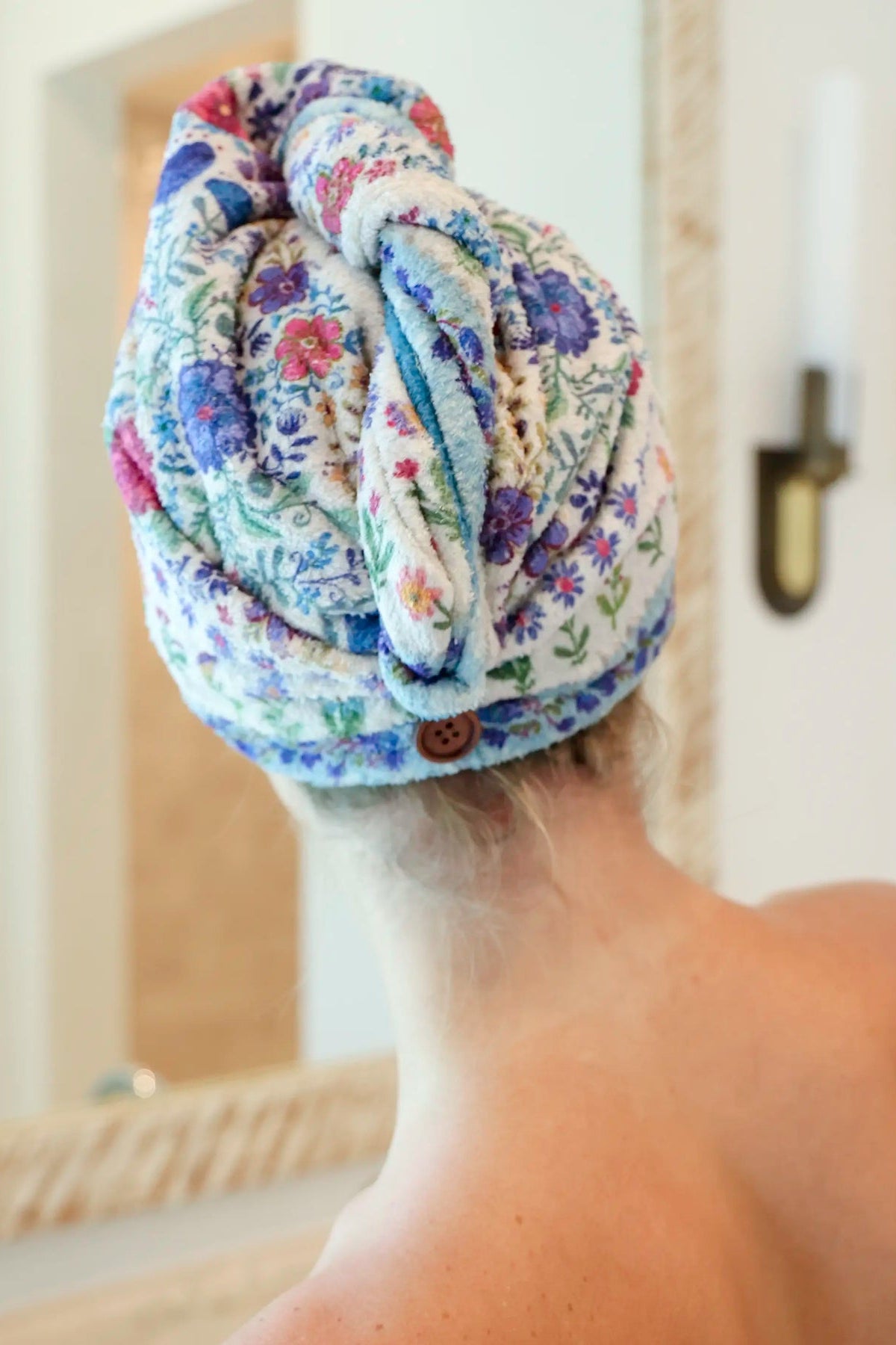 Person with a floral towel wrapped around their head in a bathroom setting