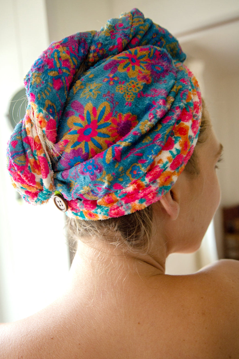 Person wearing a colorful floral towel on their head with a blurred background