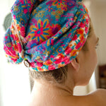 Person wearing a colorful floral towel on their head with a blurred background