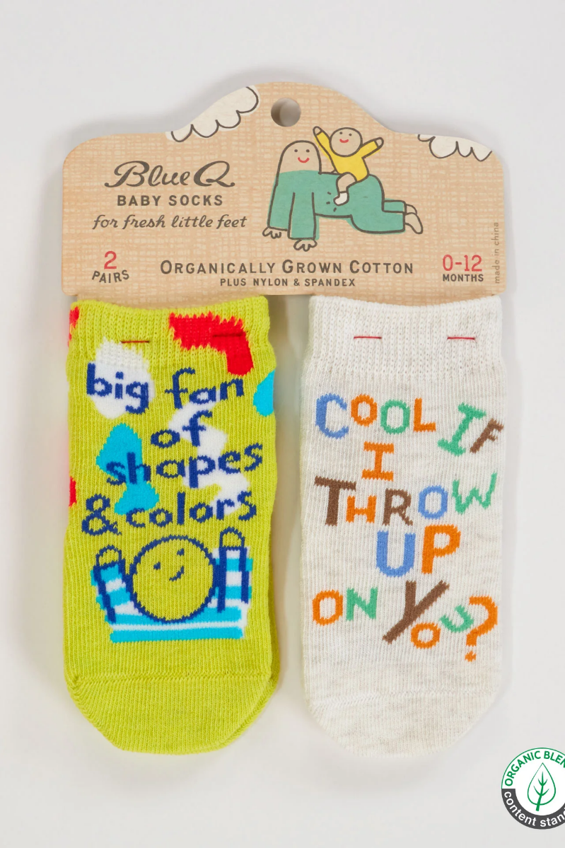 Two baby socks with humorous text on a Blue Q packaging label. 2 Pack saying: "Big Fan of Shapes & Colors", "Cool If I throw Up on You?"