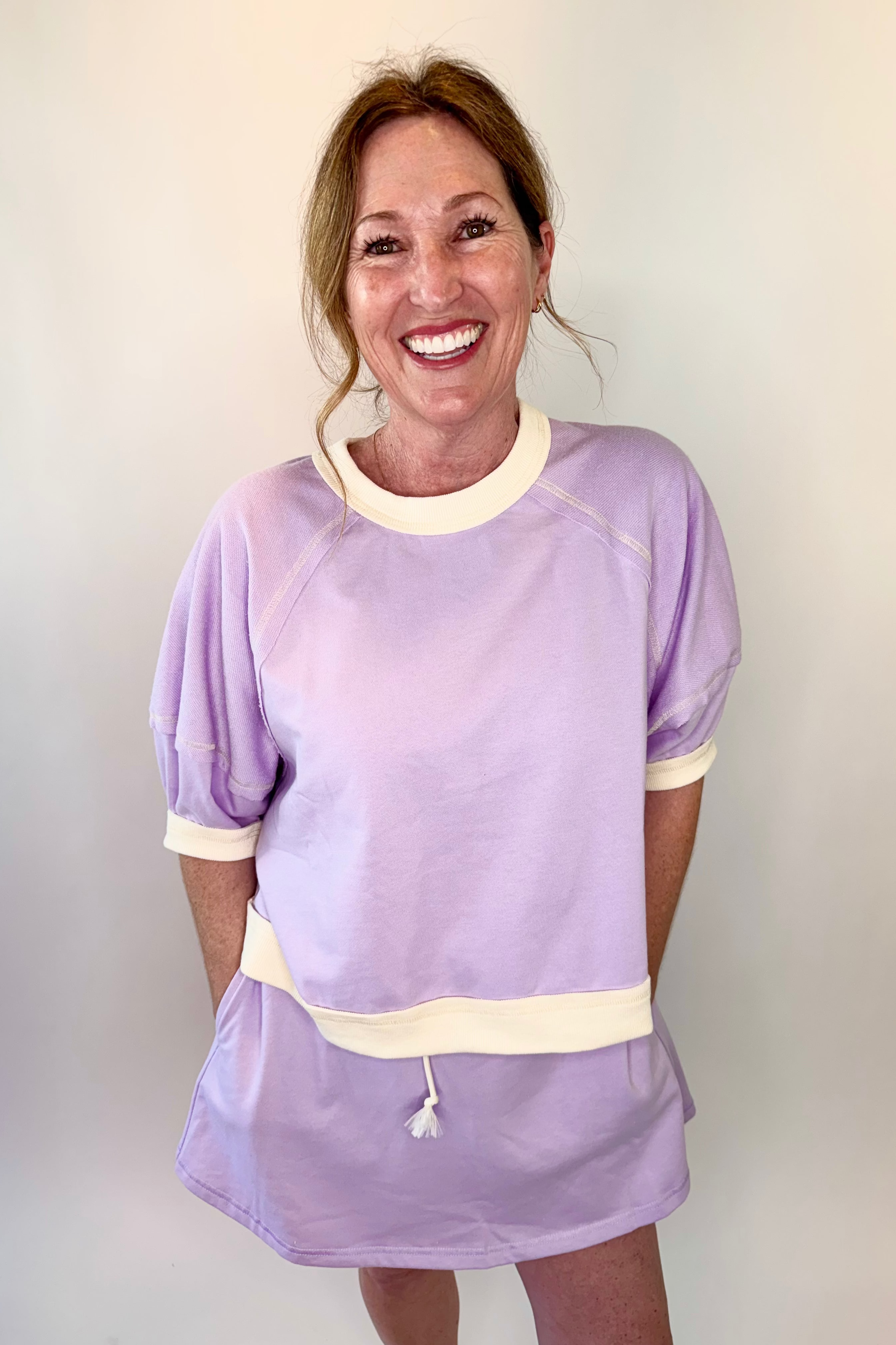 Woman wearing a light purple dress with white trim against a plain background