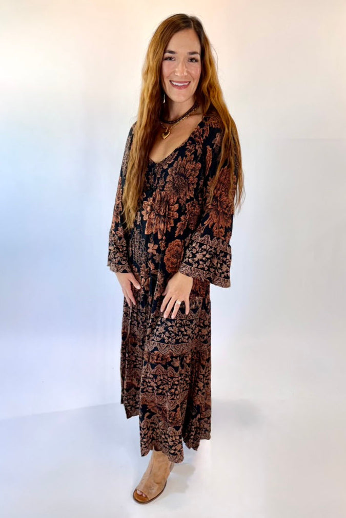 Woman wearing a long, patterned dress against a white background