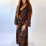 Woman wearing a long, patterned dress against a white background