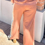 Person wearing a brown outfit standing against a brick wall.