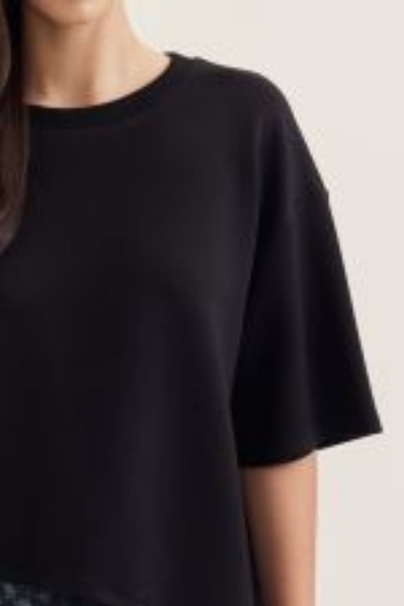 Black t-shirt worn by a person on a light gray background