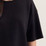 Black t-shirt worn by a person on a light gray background