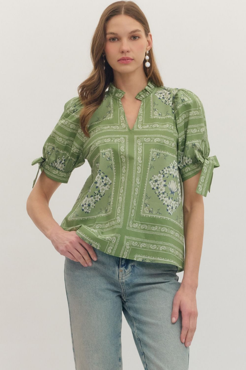 Woman wearing a green patterned blouse and jeans on a white background