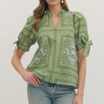 Woman wearing a green patterned blouse and jeans on a white background