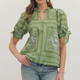 Woman wearing a green patterned blouse and jeans on a white background
