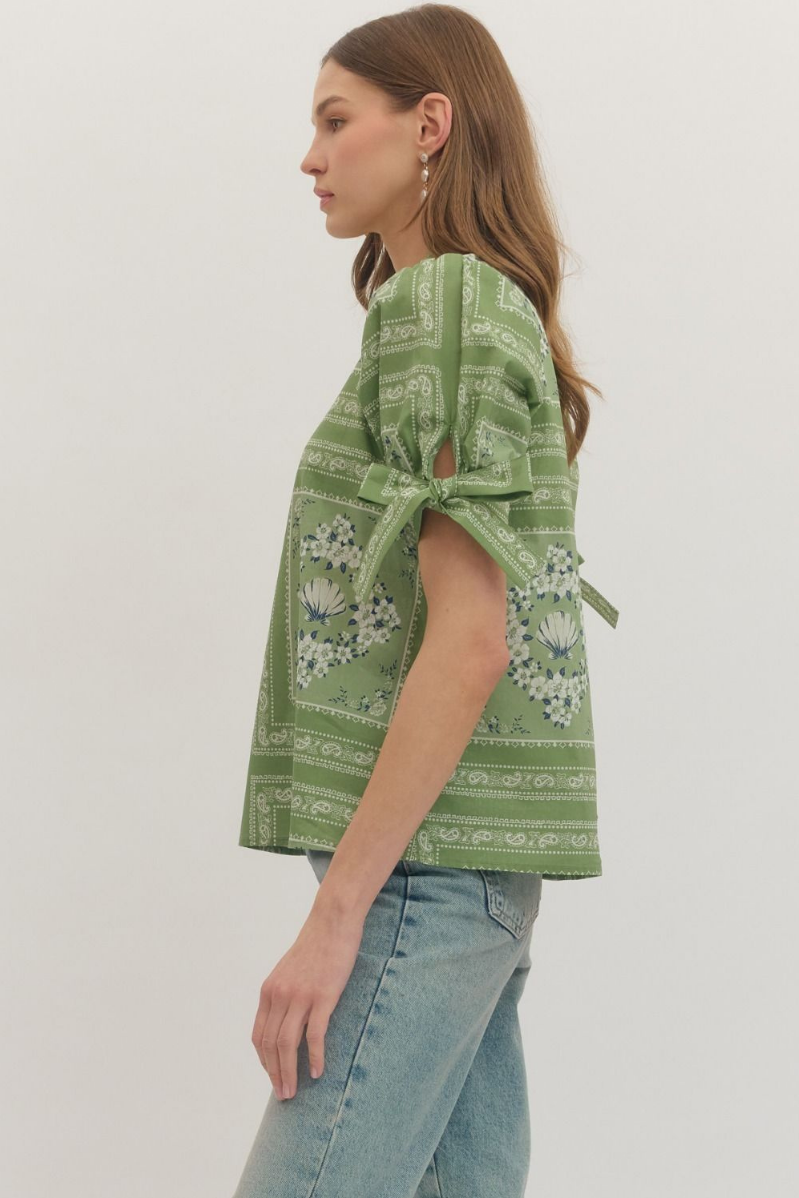 Woman wearing a green patterned top with a white background